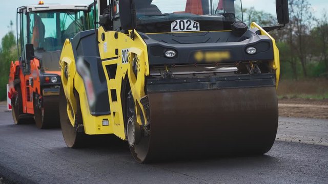 Roller machines make new asphalt roads. The asphalt paver squeezes hot asphalt.