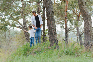 Fototapeta premium Happy father and son sitting in the park. Smiling young man spending time together with his son.