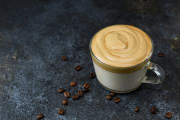 Glass cup with Dalgona coffee on dark background with copy space. Trendy quarantine homemade drink.