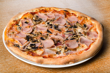 Pizza prosciutto e funghi, traditional italian oven baked: tomato sauce, mozzarella, ham, mushrooms