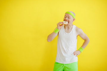 funny bald man bites a donut after training. retro style. yellow background. fun sport
