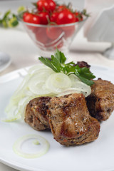 Grilled meat on a white plate in a served restaurant