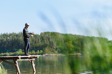 Fototapeta na wymiar A man catches a fish on a spinning fishing in the summer