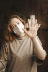 Quarantine stay at home. Bored and worried woman working alone at home in the medicine mask