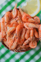 Black sea shrimp. Fresh cooked sea shrimps in a bowl on a on the background of a green & white tablecloth. Seafoood. Sea products macro. Vertical format.