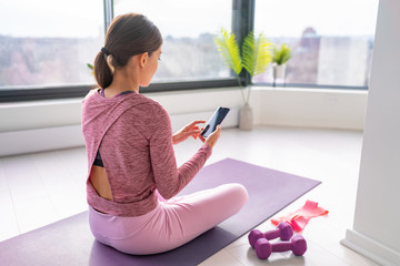 Exercise staying home woman watching fitness videos online on mobile phone yoga workout live...