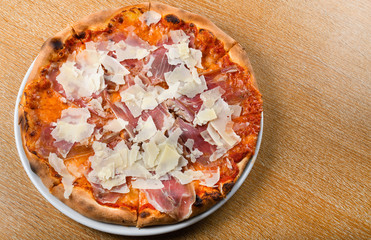 Italian pizza oven baked traditional with tomato sauce, mozzarella, prosciutto, arugula, parmesan