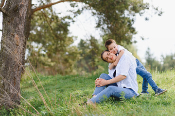 Fototapeta premium Happy family! Mother with son child playing having fun together on the grass in sunny summer day, life moment