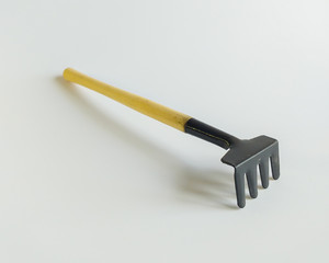 Garden rake. Separate on a white background. Miniature garden rake with a wooden handle on a white background. The concept of sodovodstvo and agriculture. Place for text.