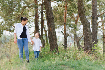 Fototapeta premium Happy young mother is playing with her baby in a park on a green lawn. Happiness and harmony of family life. Great family vacation. Good weekend. Mothers Day. Holiday. The concept of a happy family