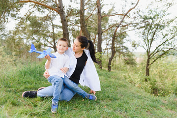 Naklejka na ściany i meble Stilish mother and handsome son having fun on the nature. Happy family concept. Beauty nature scene with family outdoor lifestyle. Happy family resting together. Happiness in family life. Mothers day.