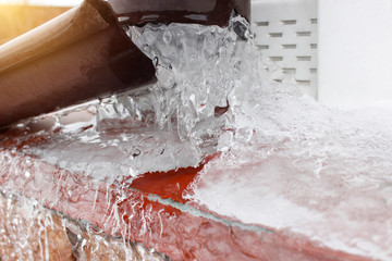 Frozen water in rain pipe of the house. Sudden freezing damages the storm sewer or gutter system.