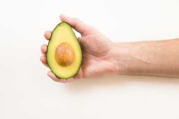 Person holding cut half of avocado with core. Closeup shot. Isolated object on white background. Fresh food or healthy diet concept