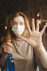 Woman with big sanitizer standing near the window in quarantine time