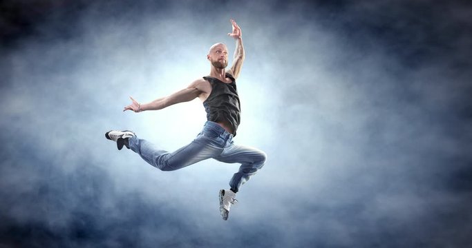 Male street dancer in a jump with fog on a backgroung.