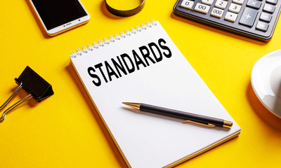 The word standards is written on white paper on a yellow background, business concept