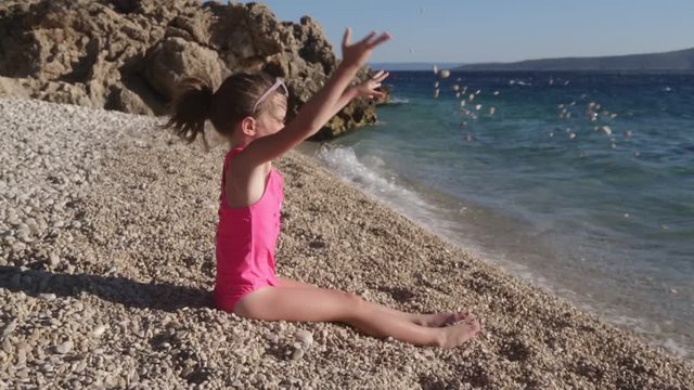 Little girl sits and plays on the beach at sunset, Makarska Riviera, Punta Rata beach, Croatia