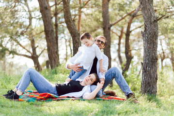 Fototapeta premium happy young family spending time outdoor on a summer day have fun at beautiful park in nature while sitting on the green grass. Happy family.