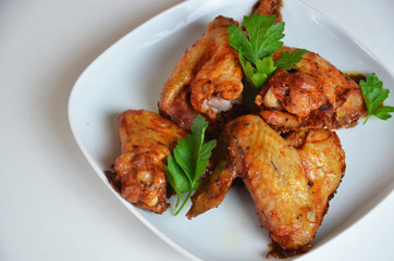 plate of chicken wings on white table red sauce in a gravy boat