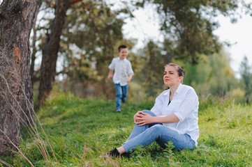 Fototapeta premium Happy young mother is playing with her baby in a park on a green lawn. Happiness and harmony of family life. Great family vacation. Good weekend. Mothers Day. Holiday. The concept of a happy family