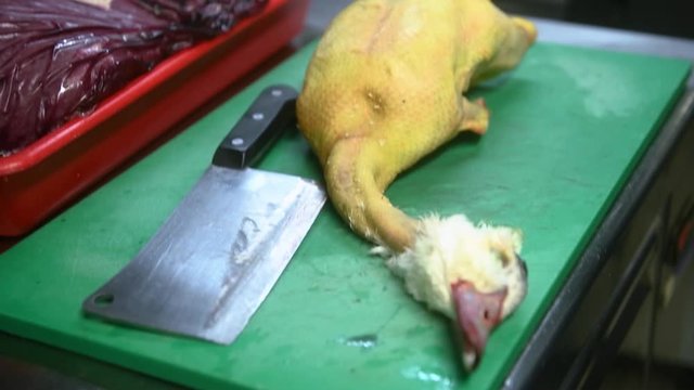 Un chef cuisinier tranche la t&ecirc;te d'un canard pour le cuisiner.