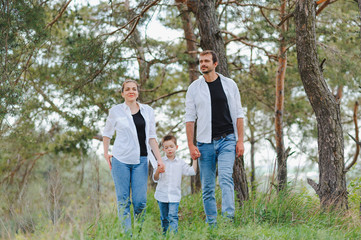 Naklejka na ściany i meble Dad, mom and little son having fun together, outdoors. Family walk in park. Happy family outdoors. Family, vacation concept
