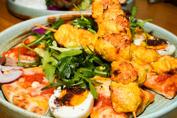 Chicken tandoori with rucola salad, egg with sumac spice, pitta bread. Asian dish