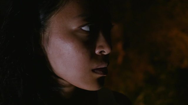 Beautiful Asian girl scared looks around in the dark