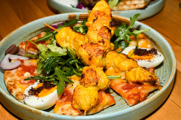 Chicken tandoori with rucola salad, egg with sumac spice, pitta bread. Asian dish