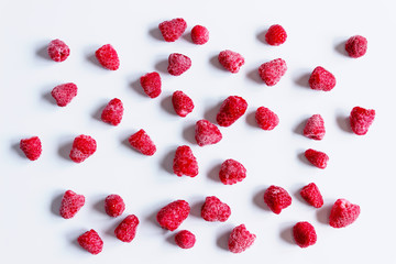 Delicious frozen raspberries are scattered on the white surface. Concept of healthy eating, vegetarianism.