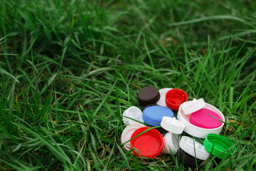 Colorful plastic bottle caps on the green grass. Volunteer charity event 