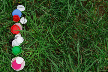 Colorful plastic bottle caps on the green grass. Volunteer charity event 