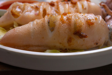 Fresh squid placed on a cutting board waiting for cooking with Knife for slicing, with lemon decorated.All on a wooden desk.