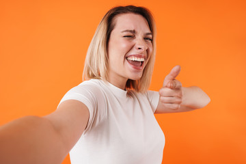 Image of woman winking and pointing finger at camera while taking selfie