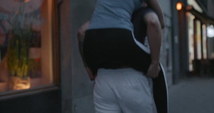 A young woman jumping up on boyfriend's back in the city.