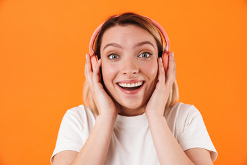 Image of cheerful young woman smiling and using wireless headphones
