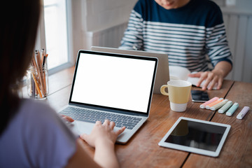 Two young employees in casual wear typing on mockup white screen computer during working day in home office. Working from home concept