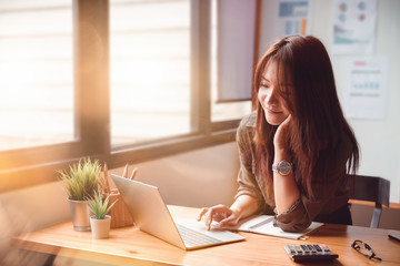 Happy casual young businesswoman working on a laptop computer in office at her home. Working at...