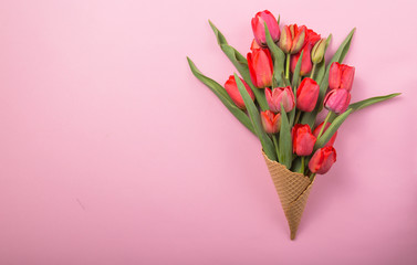 red  beautiful tulips in an ice cream waffle cone  a color background. Conceptual idea of a flower gift. Spring mood
