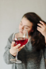 close-up of a girl in a grey sweater with a glass of red wine