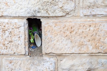 Niche or hole with garbage in the old wall in Jerusalem, Israel. Details, copy space