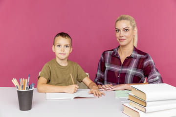 Fototapeta premium Homework together at quarantine concept. Mother with kid sitting at the desk with books and studying
