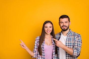 Portrait of positive cheerful team promoter woman man point index finger copyspace indicate ads promo direct way wear checkered plaid shirt isolated over bright shine color background