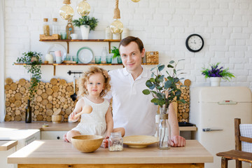 Caucasian dad and daughter, funny dad and girl hugging and cooking together in the kitchen in a bright kitchen, lifestyle and father's Day, single parents