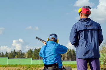 disabled shooter in a wheelchair shoots clay pigeons under the guidance of a shooting trainer 