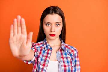 Close-up portrait of her she nice attractive lovely strict serious straight-haired girl wearing checked shirt showing palm ban sign isolated over bright vivid shine vibrant orange color background