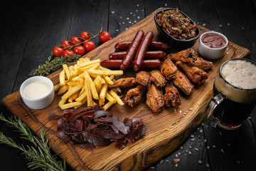 American dinner meat set. Sausages, french fries, chicken wings with sauce and beer