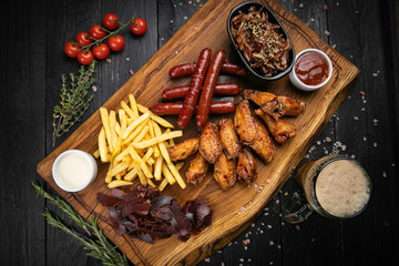 American dinner meat set. Sausages, french fries, chicken wings with sauce and beer