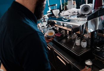 Barista preparing cappuccino on espresso machine for customer in coffee shop.