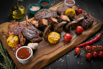 Assorted delicious grilled meat with vegetable and herbs on rustic table